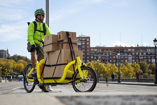 Mann transportiert mit Lastenrad Pakete