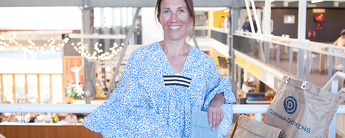 Warum nicht öfter mal ein PopUp-Store? Eine Frau mit blauem Kleid und braunen Haaren lächelt in die Kamera.
