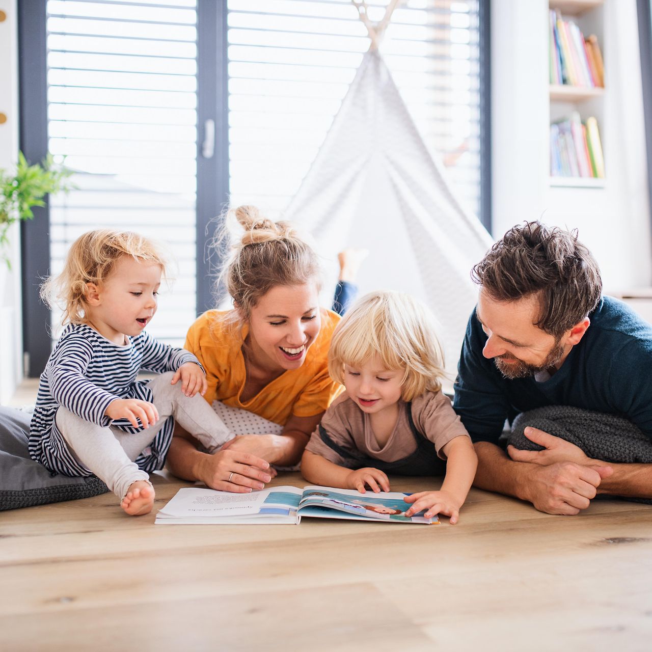 Junge Familie mit zwei Kindern liest ein Buch