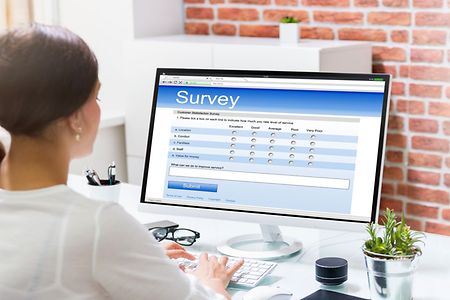 Junge Businessfrau f&uuml;llt eine Online-Umfrage am PC aus