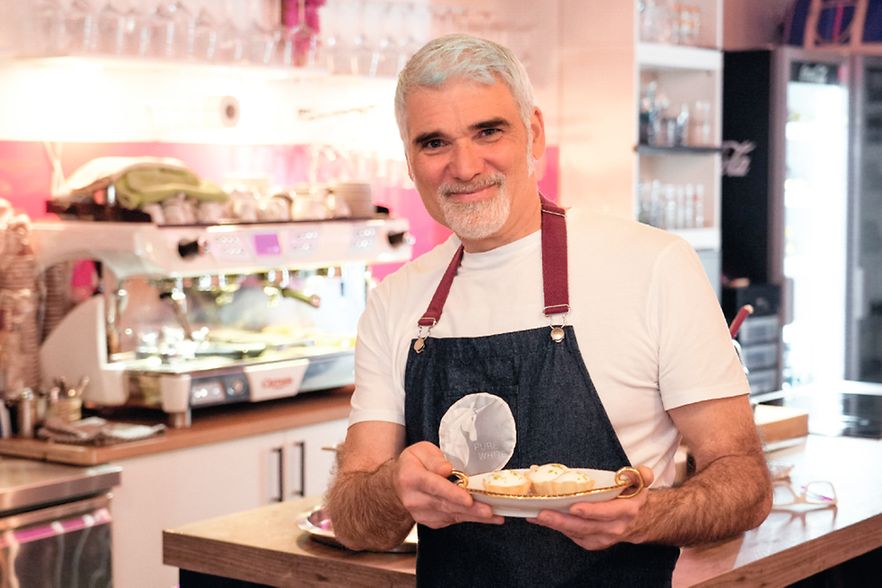 Cristiano Rienzner steht in seinem Restaurant mit einem Teller in der Hand