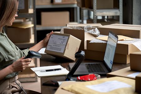 Weibliche Verk&auml;uferin scannt E-Commerce-Versandbox