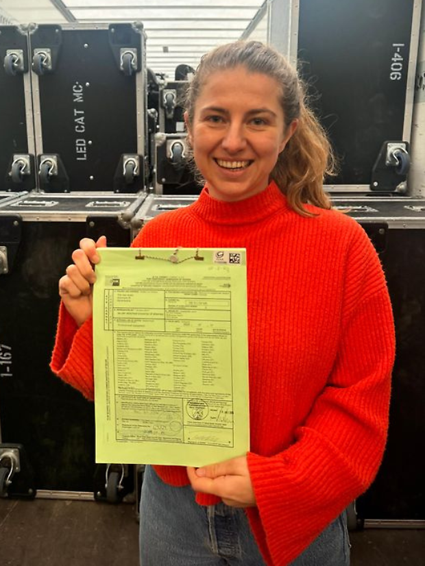 Maike Todeskino ist bei der TDA Clair GmbH für das Carnetverfahren zuständig.
Maike Todeskino steht vor den Koffern mit Equipment und hält das Carnet hoch.