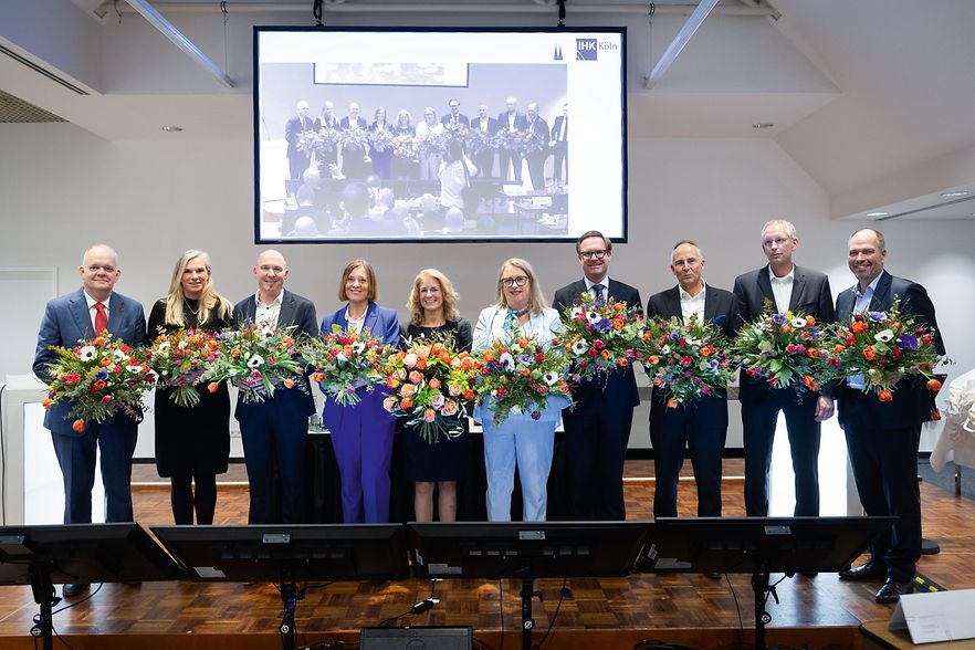 Das IHK-Pr&auml;sidium steht mit Blumenstr&auml;u&szlig;en auf einer B&uuml;hne