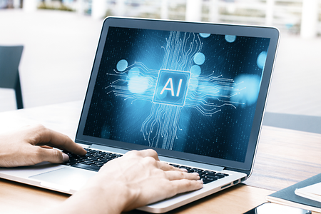 Hände eine Mannes berühren die Tastatur eines Laptops. Auf dem Bild steht: AI (Künstliche Intelligenz)