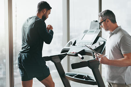 Schmuckbild; Mitarbeiter überwacht Kunden beim Sport auf Laufband