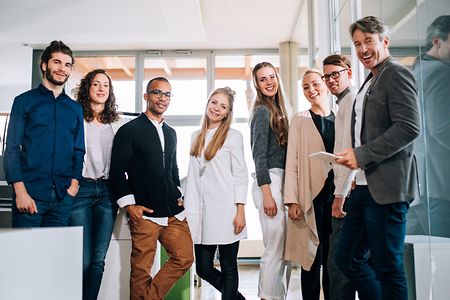 Multi-cultural group employees standing together during a office studio meeting.