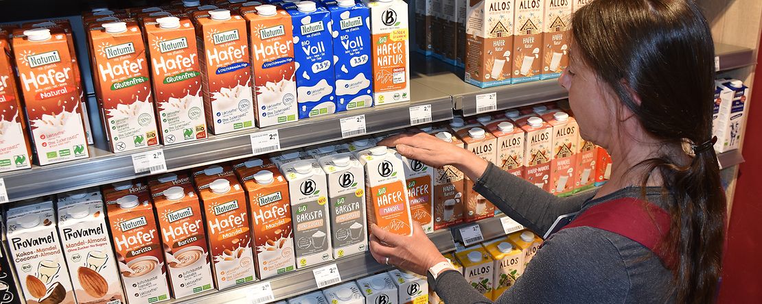 Eine Verk&auml;uferin sortiert Hafermilch in ein Regal im SuperBioMarkt an der Geiststra&szlig;e in M&uuml;nster.
