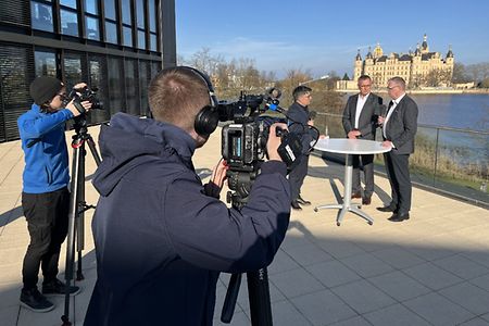 Kamerateam vorne, im Hintergrund Interviewpartner und das Schloss Schwerin