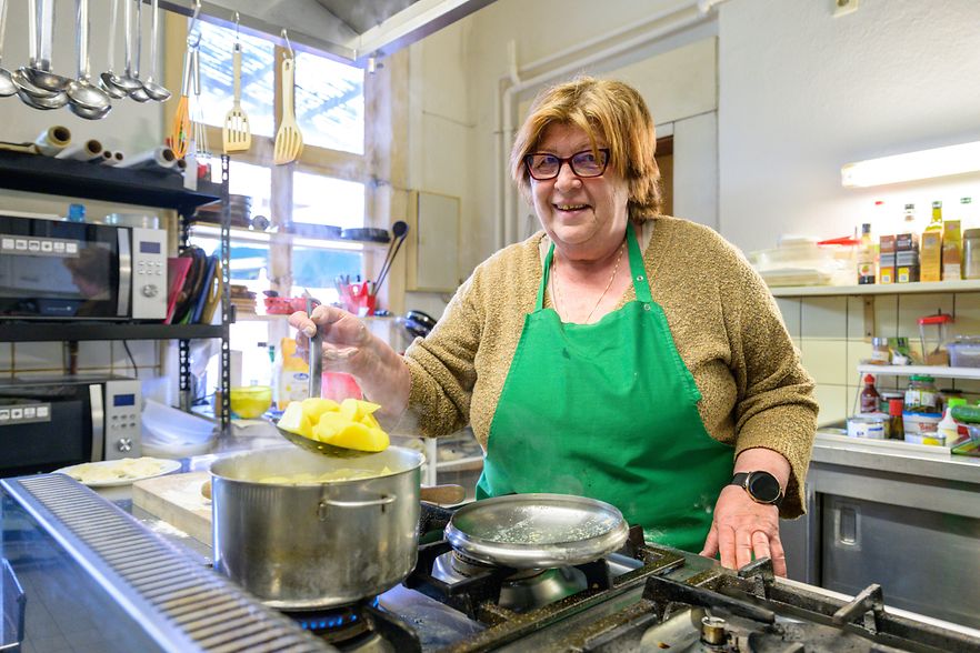 Hanna Brillowski steht in der K&uuml;che am Herd und sch&ouml;pft Kartoffeln aus einem gro&szlig;en Topf.