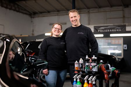 Zwei Personen in Werkstatt mit Reinigungswagen und Auto 