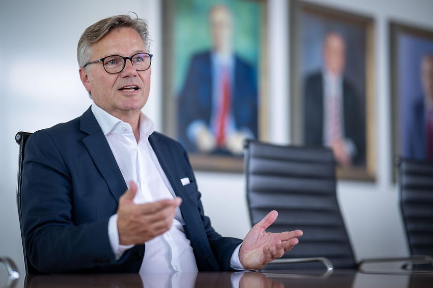 IHK-Pr&auml;sident sitzt an einem Konferenztisch, gestikuliert mit den H&auml;nden und zeigt einen ernsten Gesichtsausdruck.
