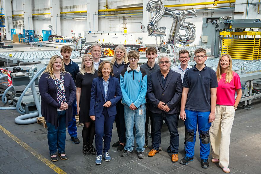 Gruppenfoto in Industriehalle mit "275"-Ballons im Hintergrund.