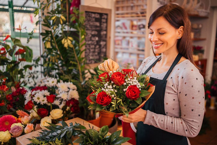 Symbolbild: Eine Floristin arrangiert einen Strau&szlig; roter Rosen