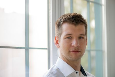 Person mit unscharfem Gesicht vor Fenster in hellem Raum