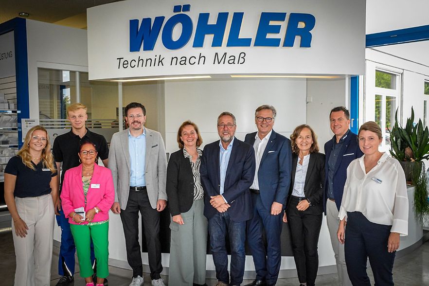 Besuchsgruppe steht gemeinsam vor dem Logo der Firma W&ouml;hler im Eingangsbereich