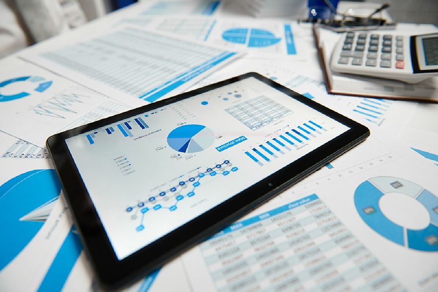Tablet mit Charts und Ausdrucken und Taschenrechner auf einem Tisch