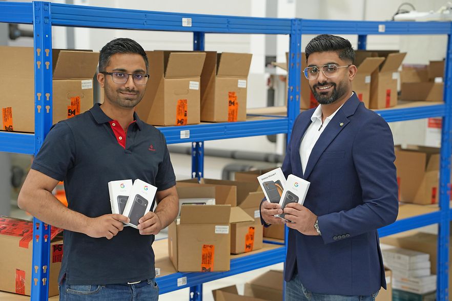 Zwei M&auml;nner mit Handy-Verpackungen in einem Lager mit Regalen