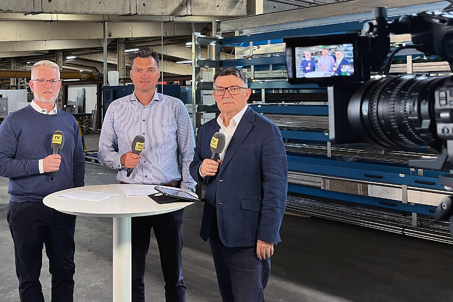 Talkrunde mit drei Männern, im Vordergrund eine TV-Kamera