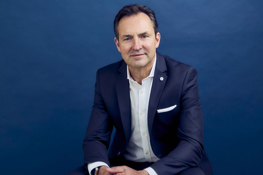 Portr&auml;t Thomas Sch&auml;fer im Anzug vor blauem Hintergrund.