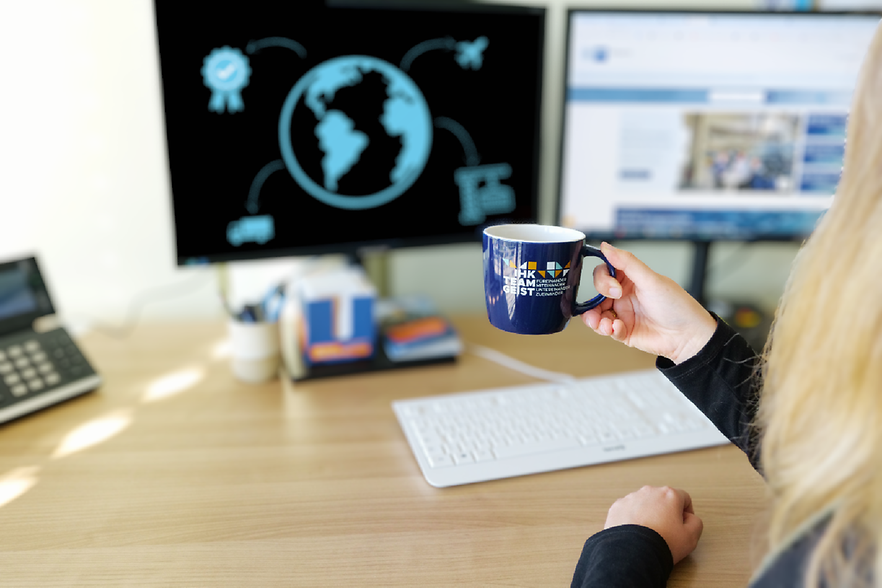 junge Frau, die vor einem PC sitzt und ein Kaffeetasse hält