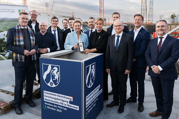 Mehrere Menschen stehen um den symbolischen Grundstein