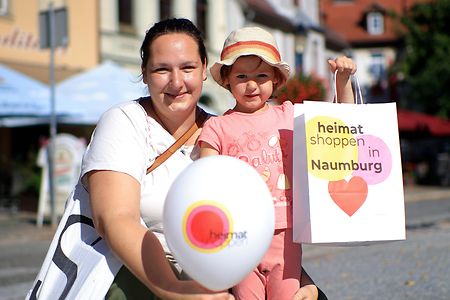 Frau und Kind halten Luftballon und Einkaufstasche