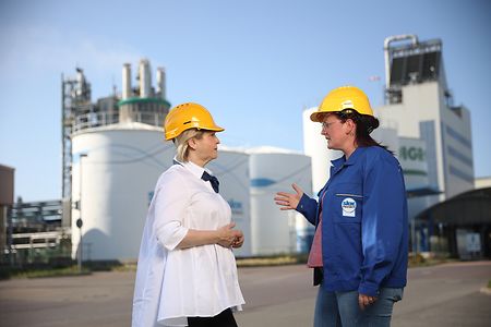 Zwei Frauen mit Bauhelmen stehen im Werk SKW Piesteritz und sprechen miteinander