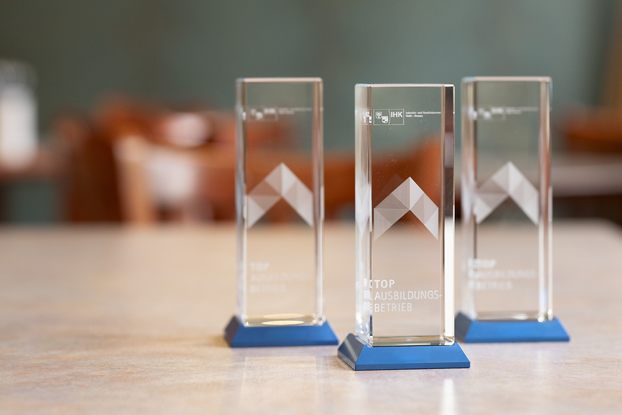 Drei Glasstelen mit der Aufschrift Top-Ausbildungsbetrieb IHK Halle-Dessau