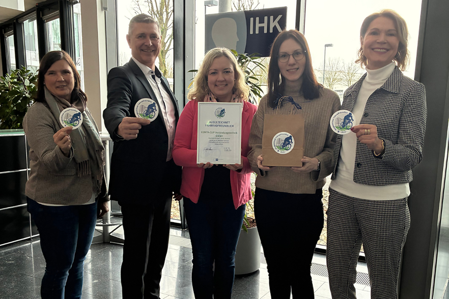 Gruppe mit Zertifikat und Siegeln im IHK‑Eingangsbereich