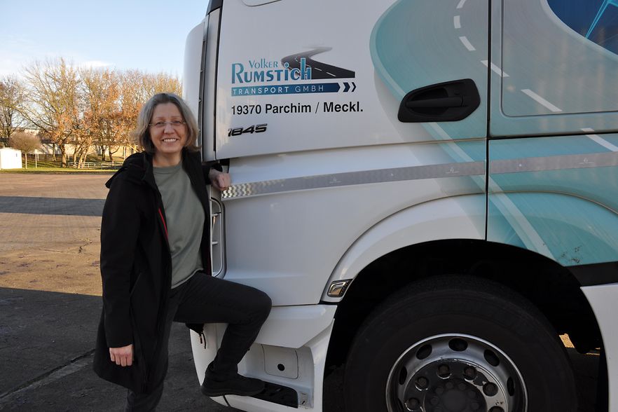 Frau l&auml;chelnd vor einem Firmenwagen