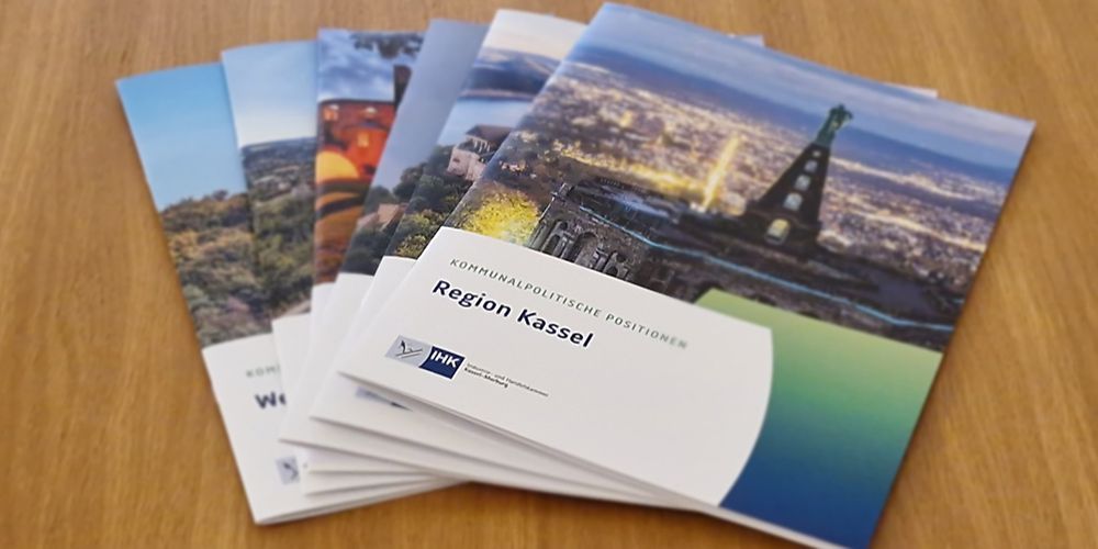 Sechs kommunalpolitische Positionspapiere liegen gef&auml;chert auf einem Holzregal 