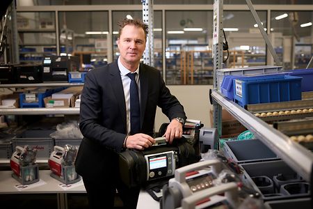 Ein Mann steht in einer Produktionshalle und h&auml;lt ein Beatmungsger&auml;t in der Hand.