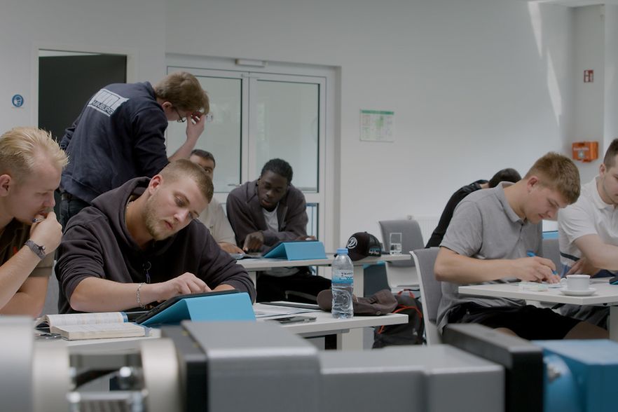 Junge M&auml;nner sitzen in einem Klassenraum und lernen.