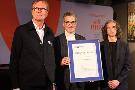 Dr. Alois Pl&ouml;&szlig;l &uuml;berreicht die IHK-Ehrenurkunde an Amran Frey und Helmut Hagner