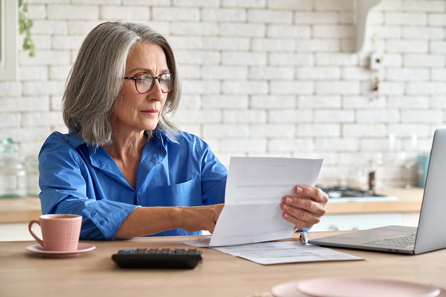 Senior mid 60s aged woman calculating bank fee with computer.