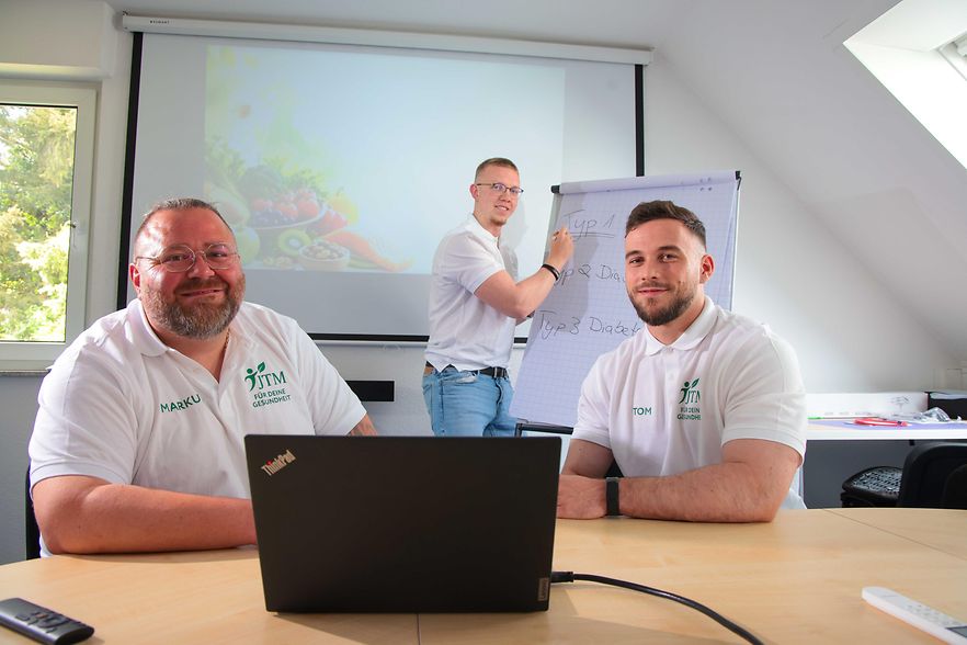 Drei M&auml;nner mit einem Laptop und einem Flipchart 