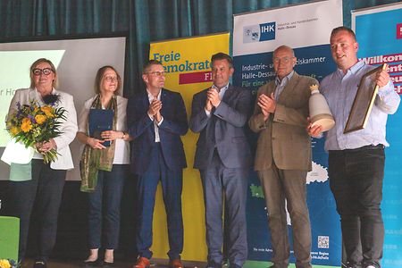 Preistr&auml;ger und Jury stehen auf einer B&uuml;hne