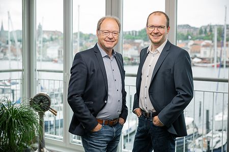 Matthias und Alexander Trost stehen nebeneinander in ihrem B&uuml;ro.