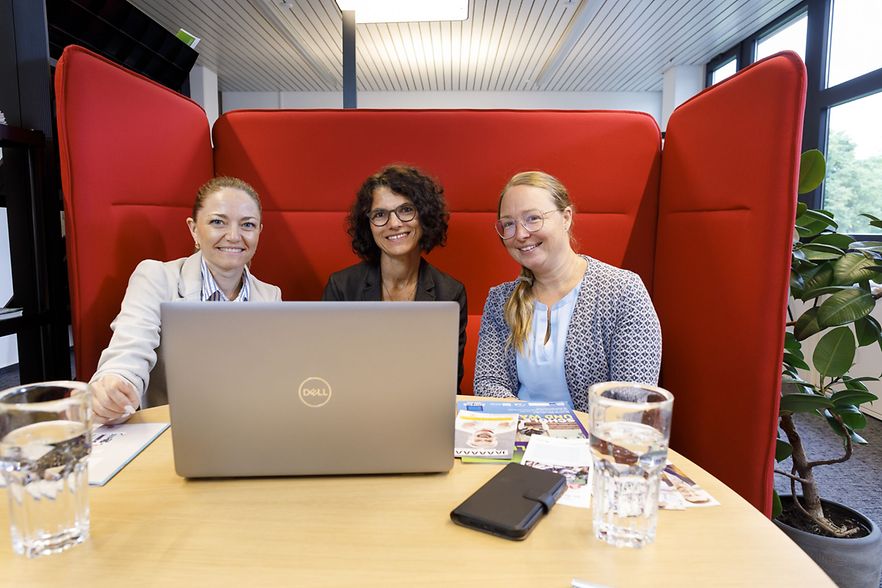 Sitzend in die Kamera schauend die IHK Kolleginnen Maria Maier, Carola Schmieder und Mona Wiedemann