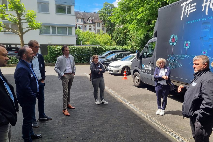 Mehrere Menschen stehen vor einem blauen Klein-LKW