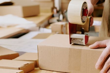 Worker,Sealing,Boxes,With,Tape,Machine,In,Shipping,Warehouse,,Preparing