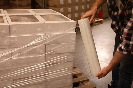 Worker,Wrapping,Boxes,In,Stretch,Film,At,Warehouse,,Closeup