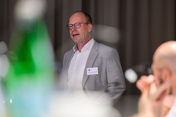 Prof. Dr. Markus Henke am Rednerpult, im Vordergrund sind unscharf Zuschauende zu erkennen.