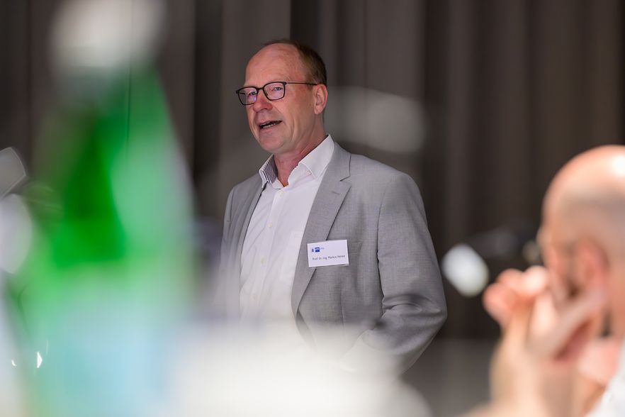 Prof. Dr. Markus Henke am Rednerpult, im Vordergrund sind unscharf Zuschauende zu erkennen.