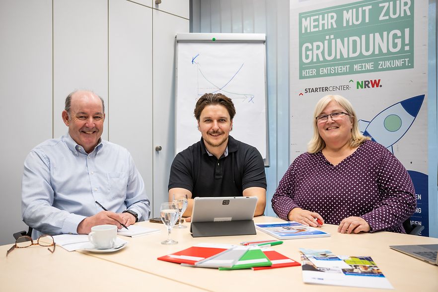 Vielberg, Kolbe, Ehm frontal an Besprechungstisch. Alle l&auml;cheln in die Kamera.