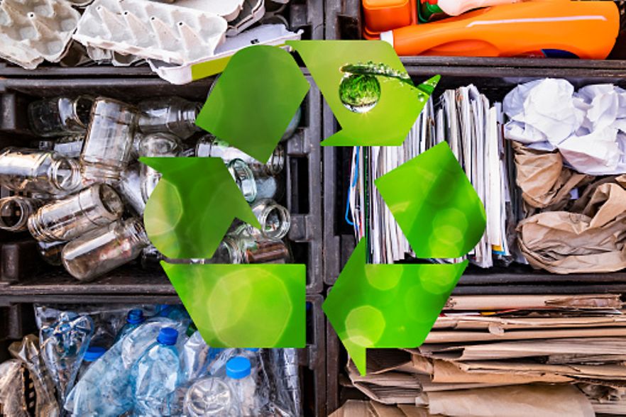 Recyclingsymbol vor verschiedenen wiederverwertbaren Materialien.