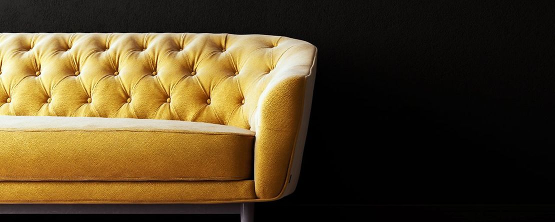 Teil eines gelben Sofas vor dunklem Hintergrund