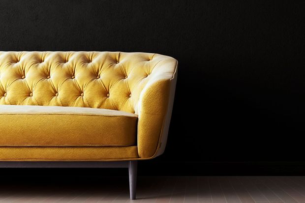 Teil eines gelben Sofas vor dunklem Hintergrund