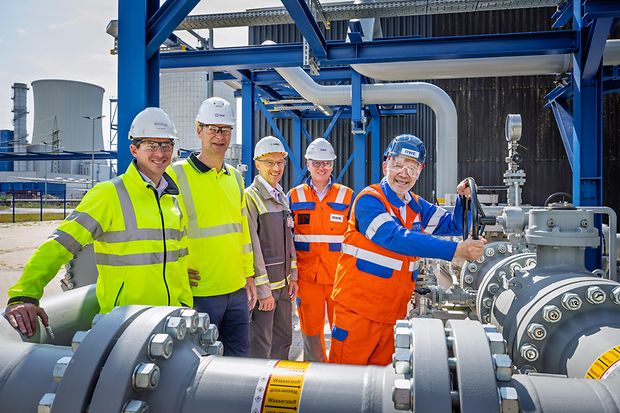 F&uuml;nf Menschen mit Schutzhelmen auf einer industriellen Anlage